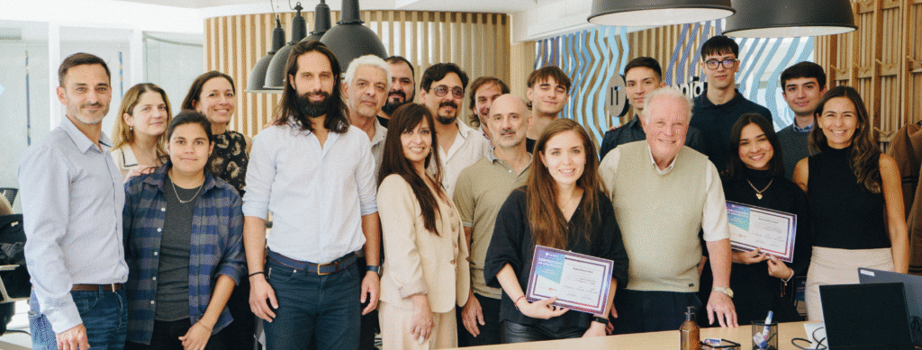 En la imagen se ve un grupo de personas de diversos géneros y edades sonrientes. Muchas muestran en sus manos el certificado de aprobación de una formación en system programming, dictada por las empresas IT Patagonia y Codeki.