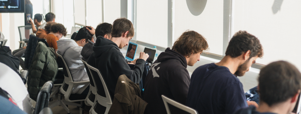En la imagen se ve a un grupo de personas jóvenes trabajando en computadoras en una oficina.