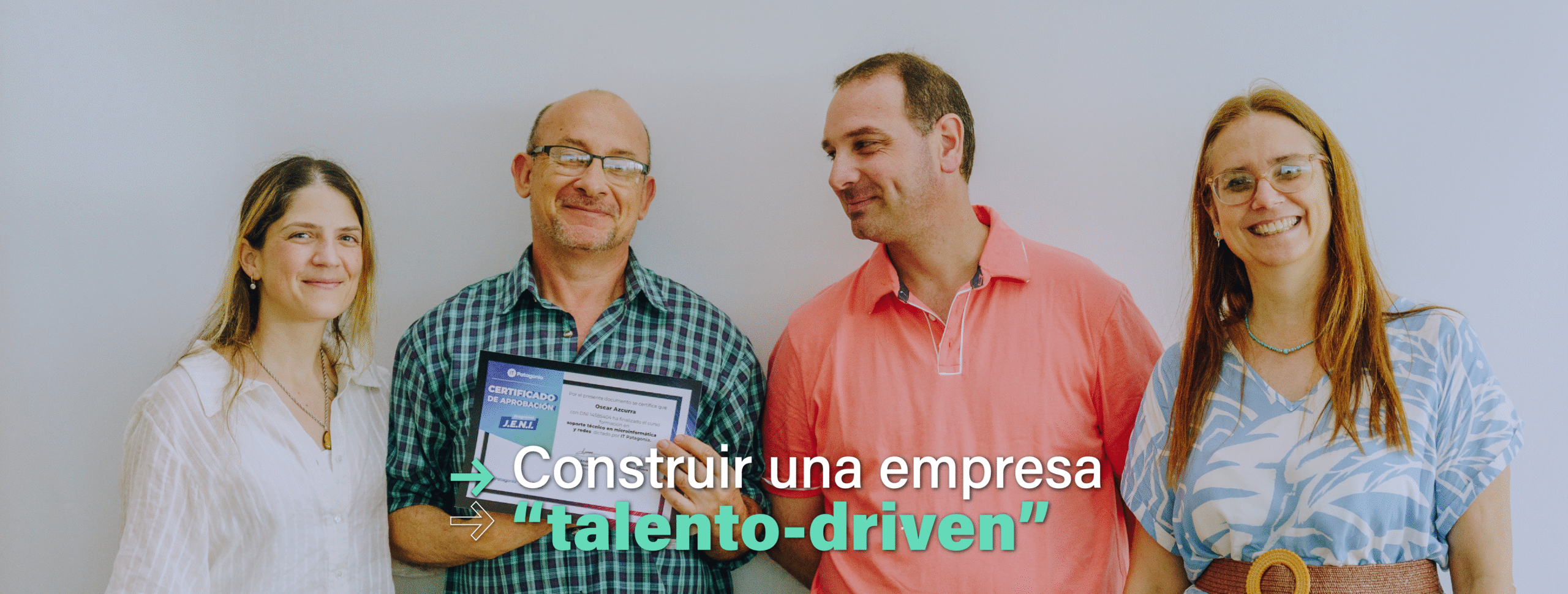 En la imagen se ve un grupo de dos mujeres y dos hombres sonriendo a cámara. Uno de los hombres sostiene en sus manos un certificado de finalización de un curso de formación en tecnología.