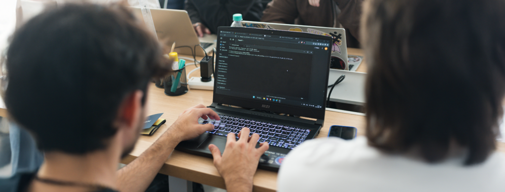 En la imagen se ven las manos de un desarrollador de sistemas escribiendo código en una laptop.