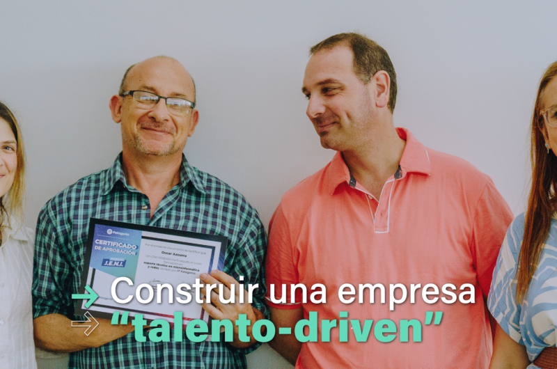 En la imagen se ve un grupo de dos mujeres y dos hombres sonriendo a cámara. Uno de los hombres sostiene en sus manos un certificado de finalización de un curso de formación en tecnología.